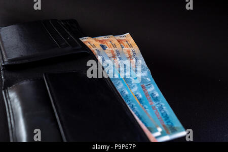 Centaines de francs dans un sac à main sur une surface noire monnaie suisse Banque D'Images