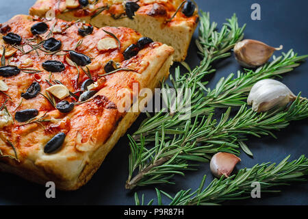 Maison traditionnelle italienne focaccia aux olives et romarin sur fond sombre Banque D'Images