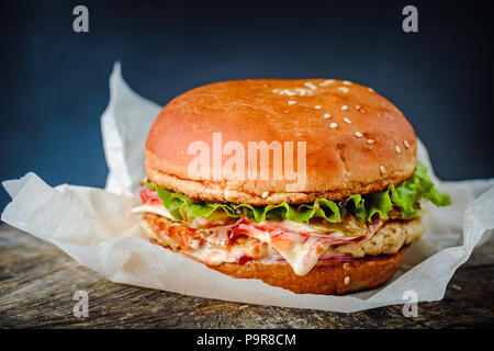 Close-up of delicious fresh burger fait maison rustique en bois sur fond sombre Banque D'Images