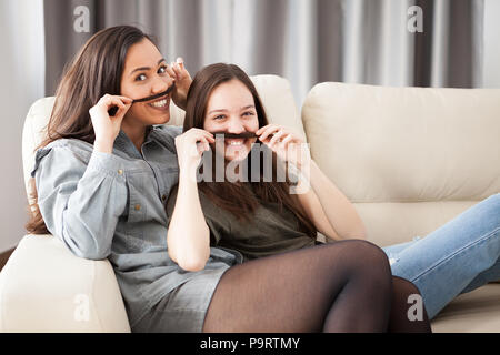 Deux soeurs jouant avec moustache cheveux. Silly funny moment ensemble Banque D'Images