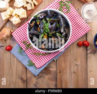 Muesli dans un bol en céramique blanc, sur une serviette rouge. Fromage sur une planche en bois et des olives, du pain. Sur un fond de bois. Espace libre pour le texte ou la publicité. Banque D'Images