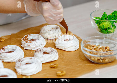 Mini Pavlova nid de meringue avec les oeufs de Pâques, des bonbons, cuisson, closeup Banque D'Images