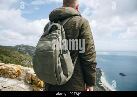 Un touriste ou voyageur avec un sac à dos est debout au sommet d'une colline et admirer la vue magnifique sur l'océan ou sur la mer. La marche ou la randonnée. Banque D'Images