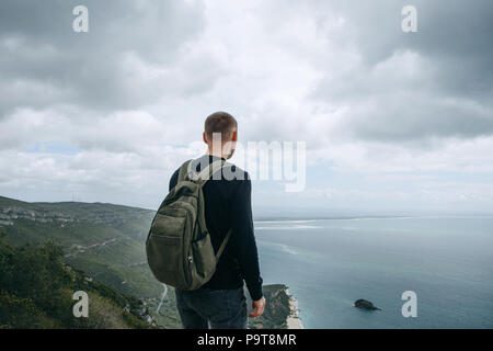 Un touriste ou voyageur avec un sac à dos est debout au sommet d'une colline et admirer la vue magnifique sur l'océan ou sur la mer. La marche ou la randonnée. Banque D'Images