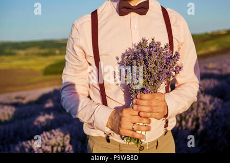 Close-up d'un bouquet de lavande dans les mains de l'époux. Banque D'Images