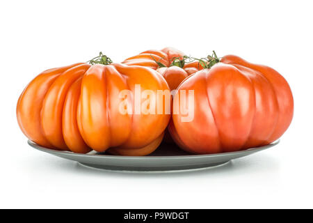 Trois tomates Boeuf gris sur une plaque en céramique isolé sur fond blanc gros fruits rouges côtelé Banque D'Images