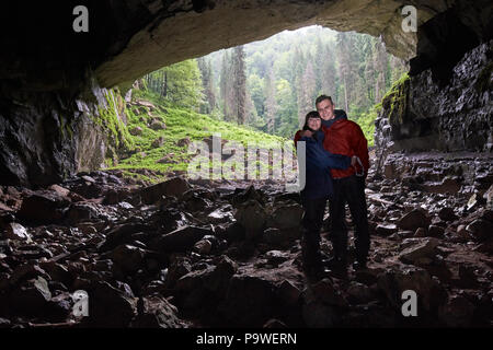 Jeune couple de randonneurs Explorer une grotte dans une montagne calcaire Banque D'Images