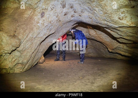 Jeune couple de randonneurs Explorer une grotte dans une montagne calcaire Banque D'Images