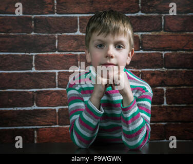 Garçon de six ans avec une expression malveillante se penche sur l'appareil photo Banque D'Images