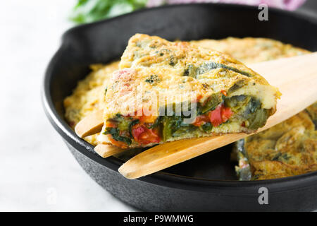 Faites de la frittata des œufs et des légumes dans une poêle de fer, sur le marbre blanc Banque D'Images