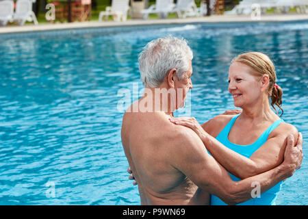 L'amour en couple de personnes âgées dans la piscine en plein air est titulaire dans les bras tendrement Banque D'Images