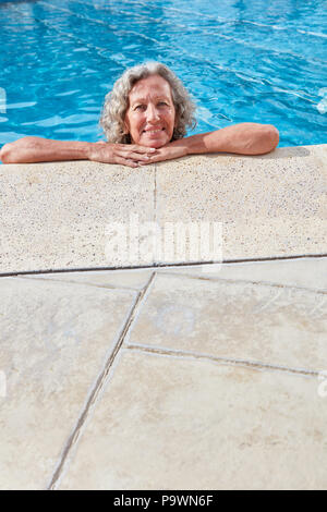 Smiling senior woman relaxing at dans la piscine extérieure chauffée en été Banque D'Images