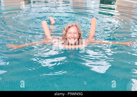 Femme senior vital en extérieure avec une aide en rehab faisant de l'aquagym Banque D'Images