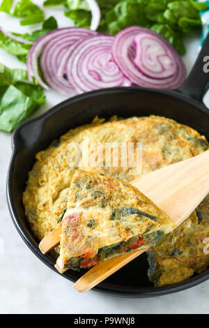 Faites de la frittata des œufs et des légumes dans une poêle de fer, sur le marbre blanc Banque D'Images