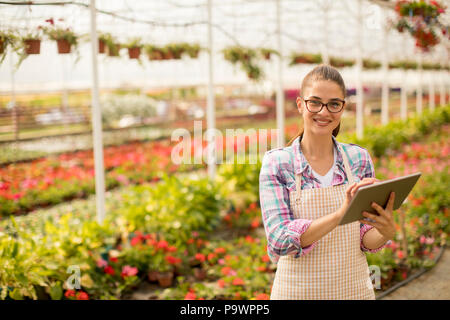 Pretty young woman with digital tablet dans le jardin de fleurs sur le printemps Banque D'Images