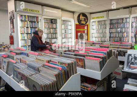 Jeune femme parcourt les disques vinyles et les albums de racks dans un magasin de disques et DVD store intérieur, Amsterdam, Pays-Bas, Hollande, Europe Banque D'Images