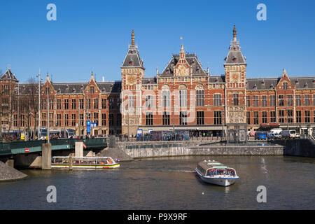 La gare la Gare Centrale d'Amsterdam, Pays-Bas, la Hollande, l'Europe avec un canal et bateaux de plaisance Banque D'Images