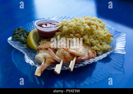 Crevettes grillées en bonne santé sur des brochettes de bois avec riz pilaf sur fond bleu du tableau est riche en éléments nutritifs et savoureux. Banque D'Images