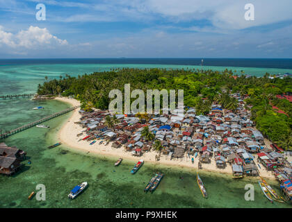Drone photo d'un très mauvais sea gypsy village Bajau à Mabul Island, Sabah, Malaisie, (Bornéo), avec la mer tropicale, ciel bleu et nuages dans l'arrière-plan. Banque D'Images