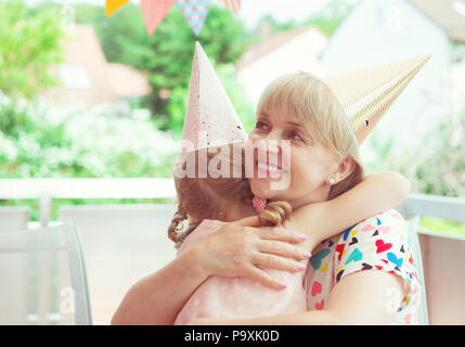 Portrait of happy grandmother hug sa petite-fille à son anniversaire sur terrasse décorée Banque D'Images