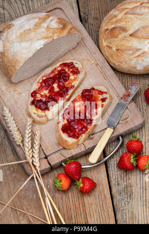 La confiture de fraise sur le pain avec du blé et des fraises sur un fond de bois Banque D'Images