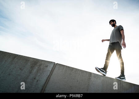 Vue latérale du parkour mâles marche sur l'athlète haut de wall Banque D'Images