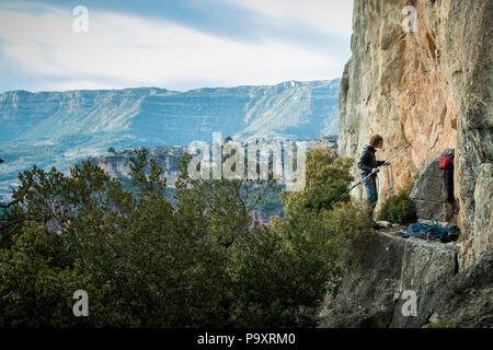 Vue éloignée sur seul aventureux male rock climber préparer stick clip à Falaise, Siurana, Catalogne, Espagne Banque D'Images