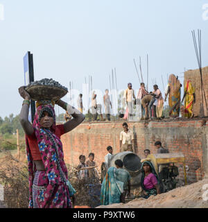 Un style de photo d'une femme indienne portant un panier sur sa tête avec les travailleurs du village sur un chantier dans l'arrière-plan Banque D'Images