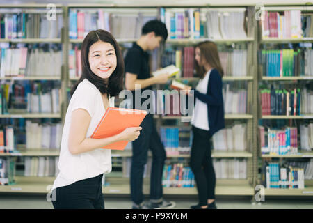 Groupe d'étudiants asiatiques d'étudier ensemble dans la bibliothèque à l'université. Les étudiants universitaires. Happy girl smiling et reding livre. Banque D'Images