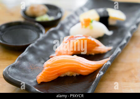 Close up of japonaise nigiri sushi situé sur la plaque noire servi avec wasabi, de la sauce de soja dans l'alimentation japonaise restaurant. Banque D'Images