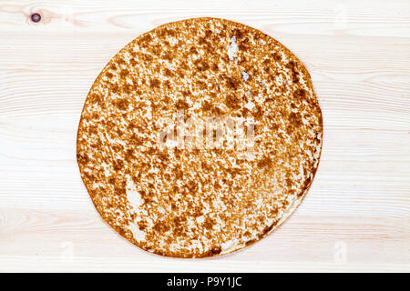 Parfumé pain rond mince allongé sur une table en bois blanc, gros plan. sur la surface de la table il y a des taches et des miettes de manger Banque D'Images