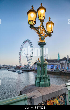 Une lampe standard sur le pont de Westminster, éclairé, avec le London Eye et le County Hall en arrière-plan. Banque D'Images
