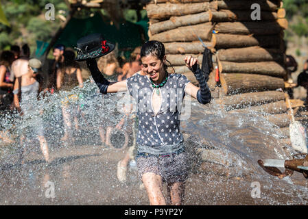 Une femme avec un chapeau en profite pour refreshung avec l'eau de la citerne qui passe à travers la scène principale de la théorie de l'psytransce music festival tenu à Riomalo de Abajo, Las Hurdes, Estrémadure, Espagne. Banque D'Images