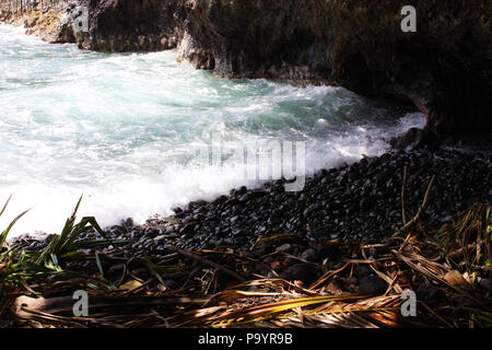 Noir, rochers lisses au bas de l'Âne réunion Sentier de l'océan Pacifique à Onomea Bay dans la région de Papaikou, Hawaii Banque D'Images