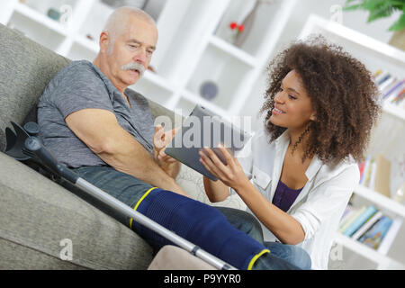 Jeune femme montrant tablet écran pour personnes âgées blessées Banque D'Images