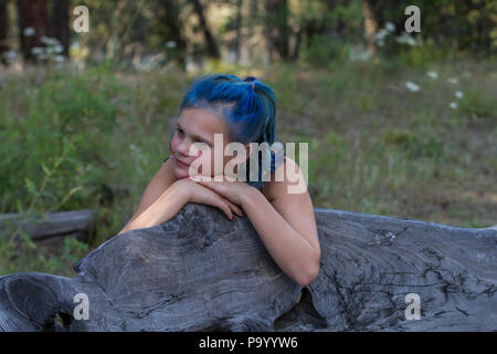 Atrtractive 8 ans, fille, dans les cheveux colorés, combinaison de saut est teint bleu lumineux, s'appuyant sur banc, portrait. Communiqué de modèle # 113 Banque D'Images