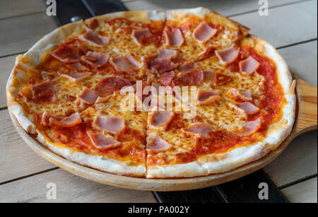 Close-up pizza jambon fromage tomate avec sources sur plateau en bois Banque D'Images