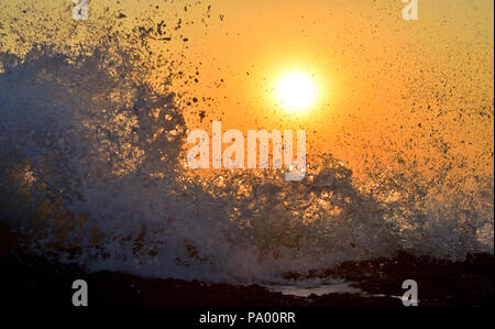 Les ondes de marée dans la mer d'Oman fracassant la plage rocheuse plage au coucher du soleil Banque D'Images