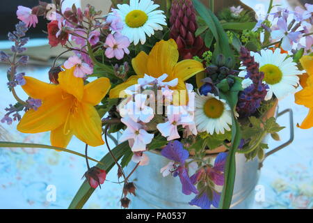 Un vase de fleurs d'été, lillies, lupins et marguerites, simplement disposés dans un petit pot ou seau apporte joie et fraîcheur à n'importe quelle table ou rebord de fenêtre Banque D'Images