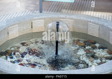 Petite fontaine intérieure dans une piscine avec pierres décoratives, galets et rochers. L'eau propre Banque D'Images