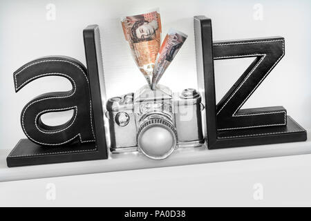 A-Z concept 'faire de l'argent à partir de votre appareil photo photographie des images qui se vendent. £10 notes aller dans la fente d'épargne en haut de style concept appareil photo Banque D'Images