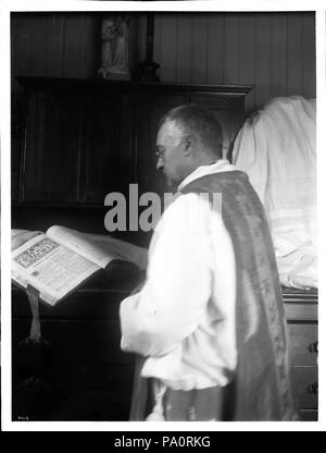 . Anglais : Père Reposo lecture à la mission de San José de Guadalupe, 1904 Photographie de Père Reposo lecture à la mission de San José de Guadalupe, 1904. Il porte une soutane, debout devant un livre ouvert sur un cabinet. Il a peu de cheveux gris et porte des lunettes rondes. Le dos et le côté gauche sont à la caméra. Un autel est visible en face de lui. Partie d'une statue d'une figue est visible assis sur l'autel. Le livre dont il lit est illustré. La section au cours de laquelle le livre est ouvert est 'Dominica de passione'. Un et demi pages sont lisibles et surtout commencer 'S[...]io ad sanctum Patrum. Introit Banque D'Images