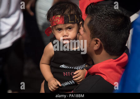 Managua, Nicaragua. 19 juillet, 2018. Un partisan du Front sandiniste de libération nationale (FSLN) embrassant son fils pendant un événement à conmemoration de la 39e anniversaire de la révolution sandiniste. Le président nicaraguayen a accusé l'Eglise catholique du pays de faire partie d'une tentative de coup d'État contre son gouvernement. Selon Ortega, l'évêques catholiques ne sont pas des intermédiaires dans la crise politique, mais plutôt une partie d'un complot putschiste. Crédit : Carlos Herrera/dpa/Alamy Live News Banque D'Images