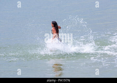 Bournemouth, Dorset, UK. 20 juillet 2018. Météo France : chauds et humides avec soleil voilé à Bournemouth, en tant que chef de la mer sunseekers à plages de Bournemouth pour profiter du beau temps. Young woman in bikini s'amusant en marche et de s'éclabousser dans la mer. Credit : Carolyn Jenkins/Alamy Live News Banque D'Images