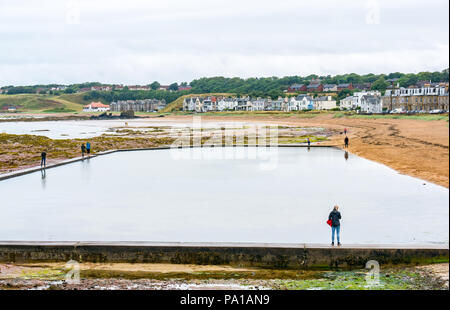 North Berwick, East Lothian, Ecosse, Royaume-Uni, le 20 juillet 2018. Un matin brumeux est un soulagement pour les jardiniers et les agriculteurs à une pause de la canicule de l'été, mais un jour humide pour les visiteurs de la ville de bord de mer. Certaines personnes ont apprécié une promenade sur la plage à Milsey Bay malgré le temps gris Banque D'Images