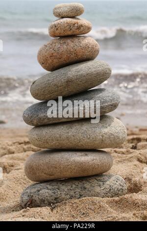 Un zen-comme tas de pierres lisses équilibré sur une plage à Block Island, Rhode Island. Banque D'Images