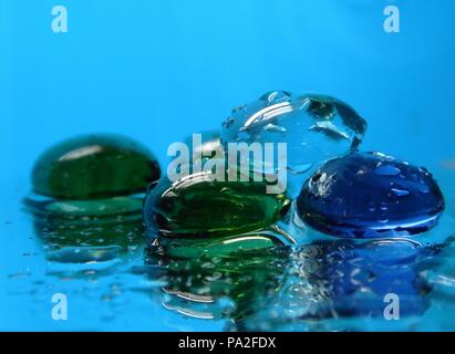 Les Roches en verre coloré sur miroir avec de l'eau Banque D'Images