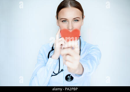Portrait d'une femme médecin avec coeur rouge en mains isolé sur fond bleu, centre de cardiologie, soins de santé concept Banque D'Images