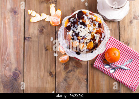 Gâteau fait maison avec les tangerines et les amandes, avec le chocolat. Sur une assiette blanche, pour le petit-déjeuner. Fond de bois, de l'espace pour écrire du texte ou de la publicité Banque D'Images