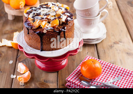 Gâteau fait maison avec les tangerines et les amandes, avec le chocolat. Sur une assiette blanche, pour le petit-déjeuner. tasses pour le thé. fond de bois, de l'espace pour écrire du texte ou de la publicité Banque D'Images